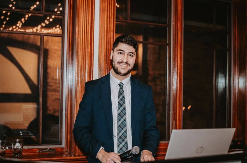 DJ Marc Fayad, founder of SpinVibe Entertainment, holding a microphone at a wedding reception