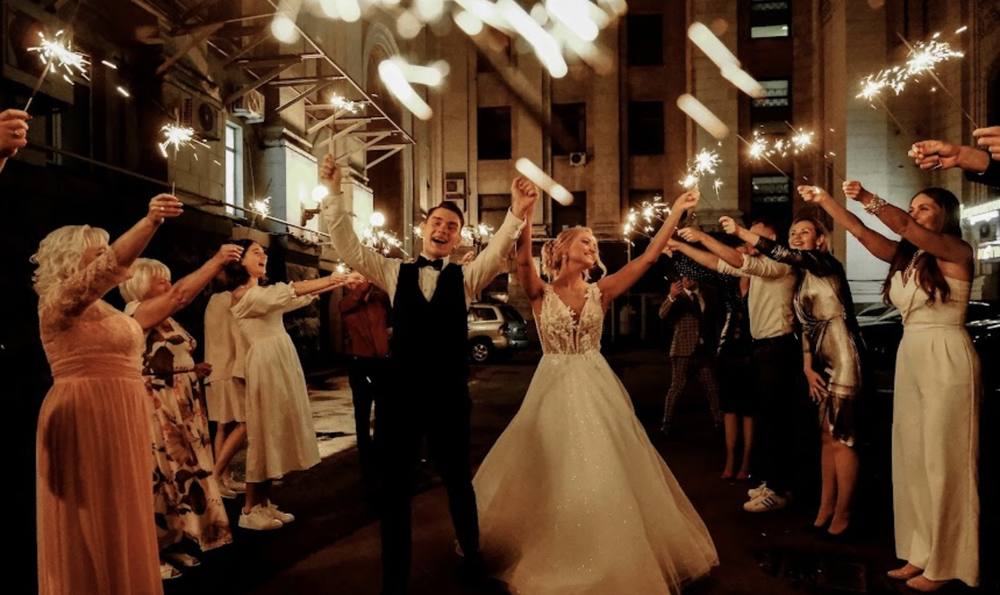 Bride with hands up surrounded by dancing guests