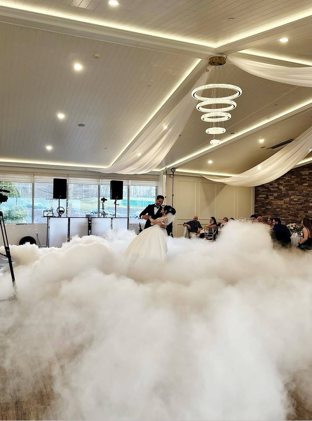 Bride and groom's first dance on a cloud of low fog in a ballroom