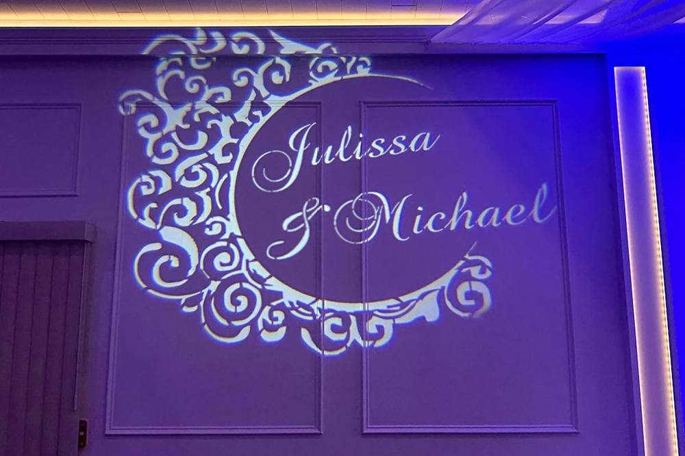 Custom monogram with the couple’s names projected in light on a reception wall