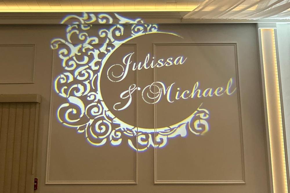 Custom wedding monogram projected in white light on a reception wall