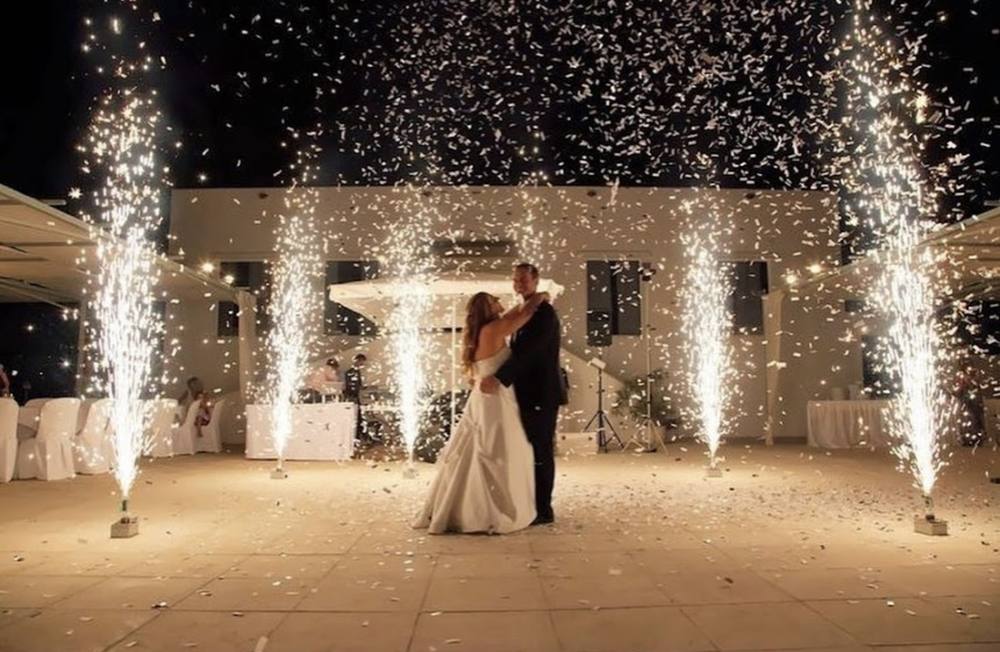 Couple dancing between two cold spark fountains under string lights