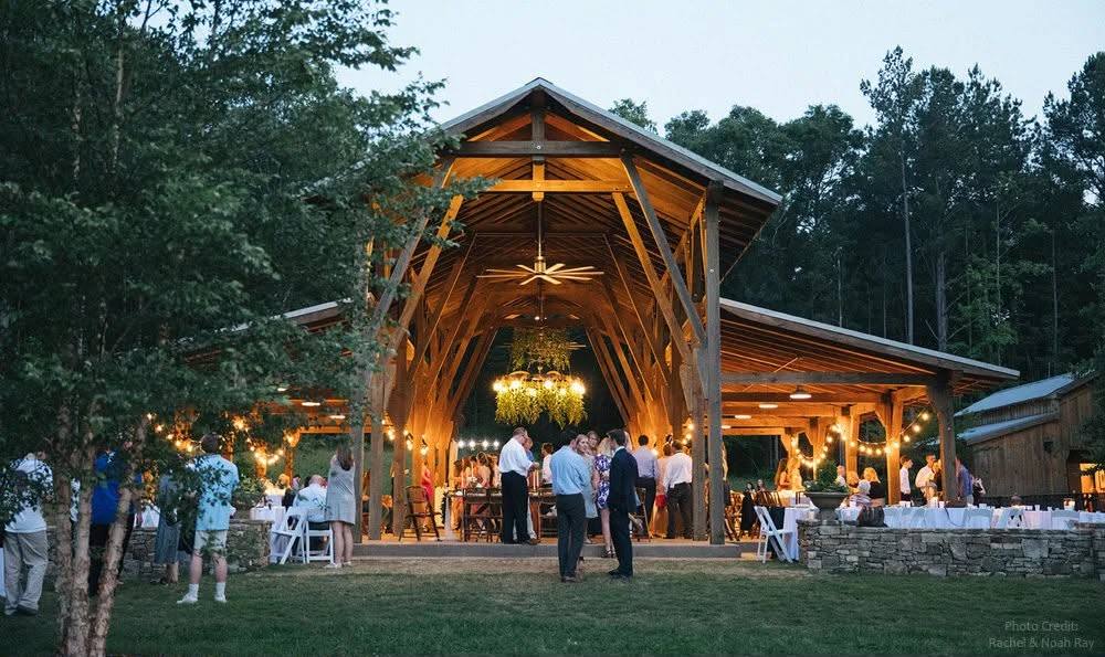 Open-air timber pavilion lit with string lights for a wedding reception