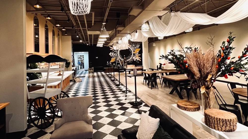 Insieme Event Venue's open event space with checkered floor, bar and draped ceiling