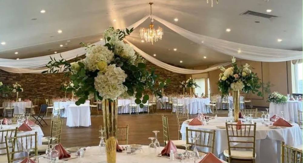 Wedding reception tables set with gold chairs and white floral centerpieces