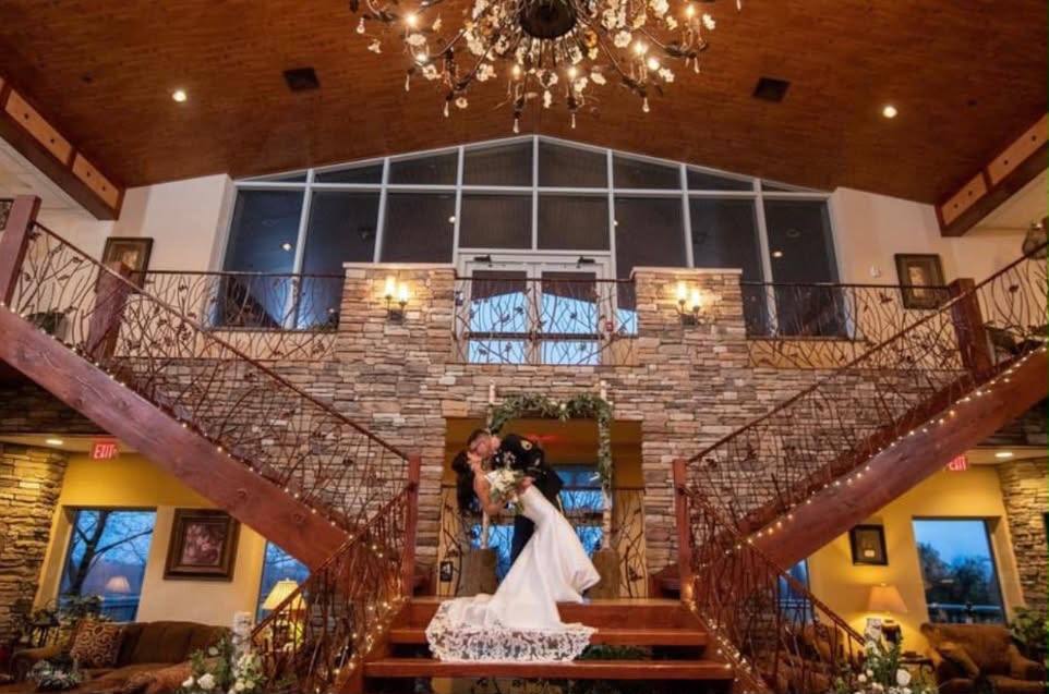 Couple kissing at the foot of the grand double staircase at Woodstone Country Club